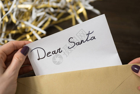 女用手把圣诞老人的信放在信封图片
