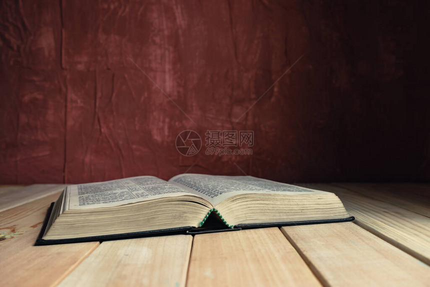 在一张旧木桌上打开圣经美丽的红墙背景图片