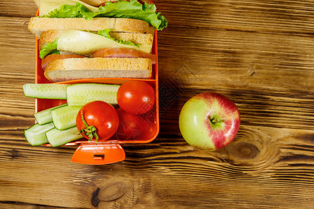 苹果和午餐盒配有三明治和新鲜蔬菜图片