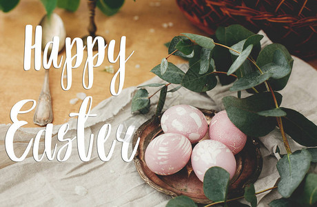 复活节快乐文本复活节问候刻字现代复活节彩蛋与桉树枝在质朴的木桌上图片