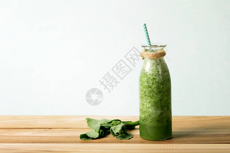 在木制桌上的玻璃瓶中装有健康新鲜绿色凉冰果汁图片