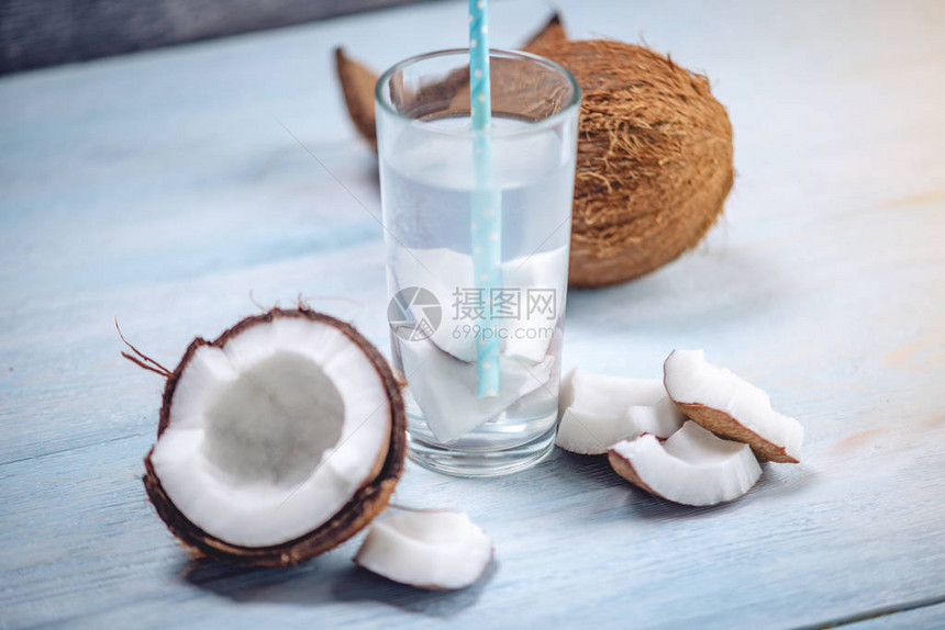 椰子水的成分与一个开放的椰子与蓝色木制背景上的白色果肉广泛用于美容和水疗的有机健康图片