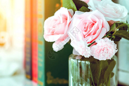 白色桌上的玻璃花瓶中美丽的人造粉红色玫瑰图片
