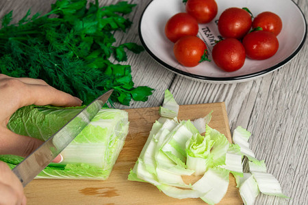 女用刀子蔬菜沙拉西红柿和在竹制板上的白桌木块切割手食品早餐天然产图片
