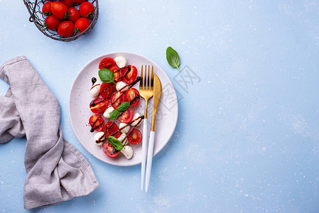 蓝色背景中樱桃番茄和婴儿马苏里拉奶酪的Caprese沙拉图片