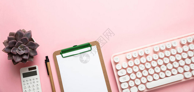 计算机键盘和笔记板以粉红背景为基图片