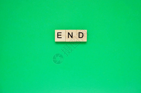 词尾在绿色背景上带有刻字的木块绿色表面带有字母的木图片