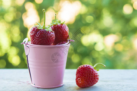 外面桌外的阳光小桶新鲜草莓底图片