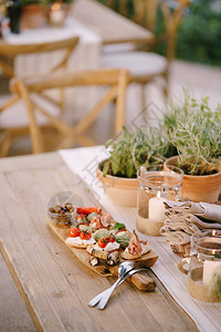 锅里花朵旁的餐桌上有冷切和餐具的木制切割板背景图片
