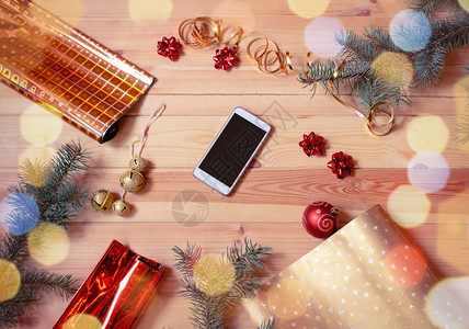 被冷杉树枝包装纸卷和圣诞装饰品包围的智能手机为假期做准备带有复制图片