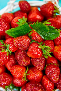 蓝色桌子上成熟的红草莓背景图片