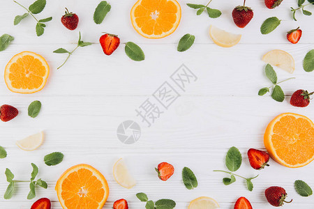 以白木桌的柑橘水果叶子和草莓制成的模型顶层视图片