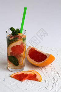 清爽的夏季自制红葡萄柚鸡尾酒与白色背景上的绿薄荷排毒柑橘鸡尾酒健图片