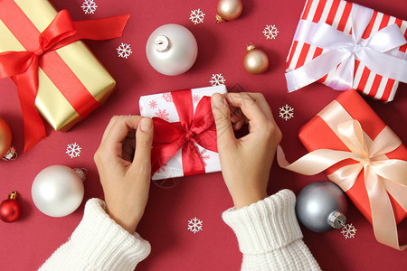 女手在彩色背景顶视图上包裹圣诞或新年礼物图片