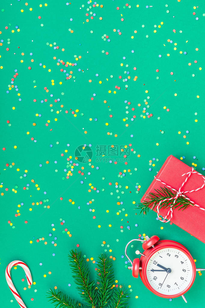 新年或圣诞节图案平躺顶视图与红色闹钟十二午夜冷杉树枝圣诞假期庆祝绿纸明亮多彩五纸屑背景模板文本设图片