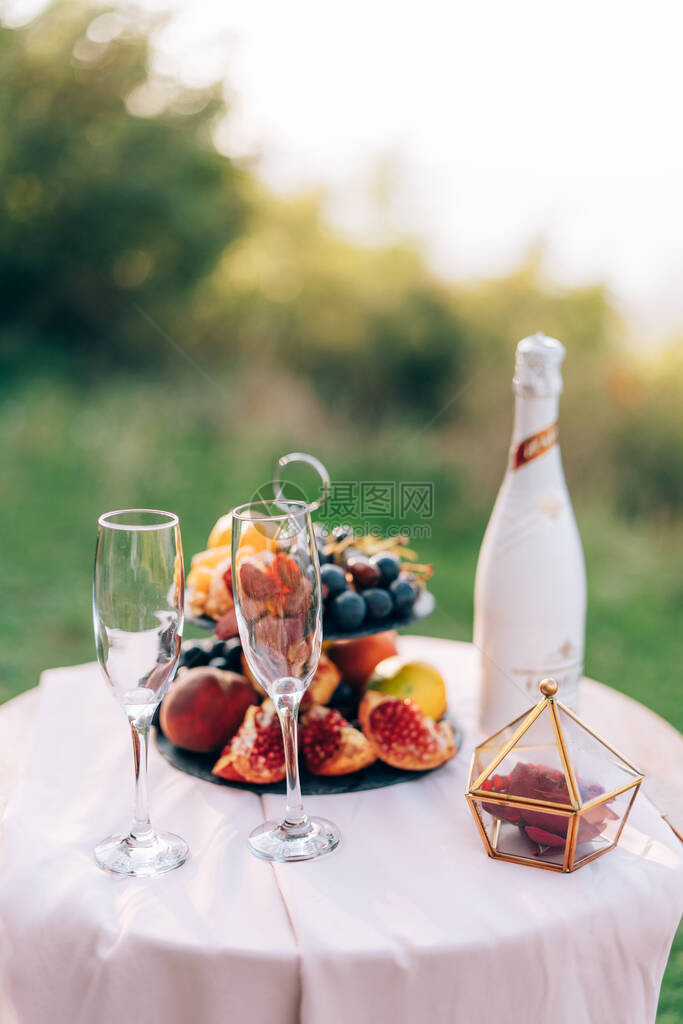 一桌白布两杯香槟和一本带有天然水果的书架图片