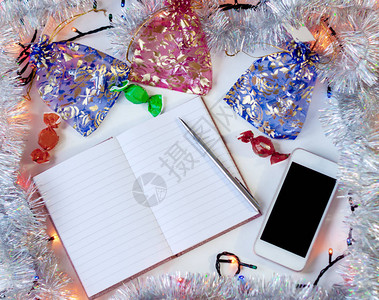 用笔和电话做笔记的笔记本圣诞花环背景上图片