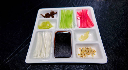 黑桌上的塑料盘子上的传统零食图片