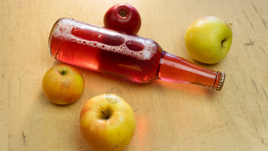 背景上有一瓶红苹果和新鲜苹果放在桌子图片