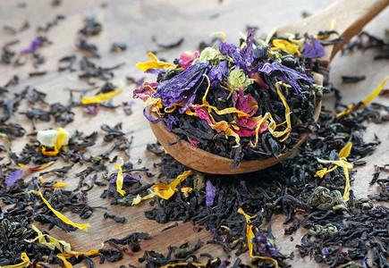 混合茶黑茶干花瓣和水果木勺中的干图片