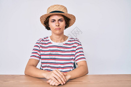 身着便衣和帽子坐在桌边的年轻西班牙女感到沮丧图片