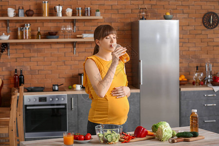 年轻孕妇在厨房喝果汁图片