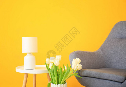 彩色墙附近的扶手椅花束和桌子背景图片