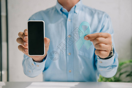男持有蓝色感知带和用空白屏幕的智能手图片