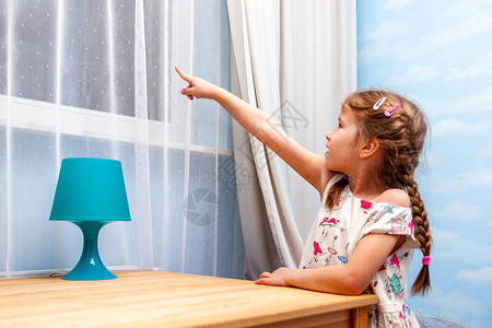 快乐的小女孩兴奋的孩子用手指着窗外微笑的孩子图片