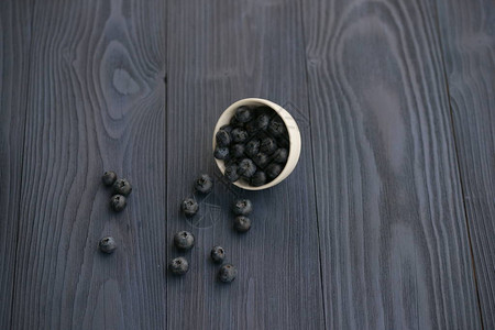 白色杯子蓝莓深色木桌上洒浆果背景图片