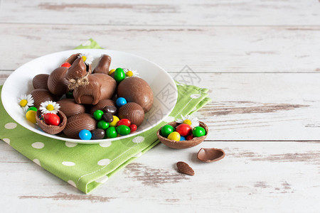 巧克力复活节鸡蛋和兔子放在木制背景的盘子上图片
