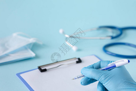 蓝色背景上的医学概念听诊器药丸平板电脑记事本纸笔医用手套医用口图片