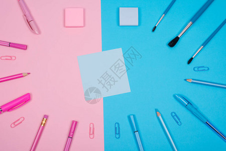 粉色和蓝色分离背景上的空白蓝纸贴和粉色和蓝色的学校或办公用品图片