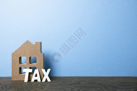 房屋模式对蓝背景的木制餐桌征税抵押图片