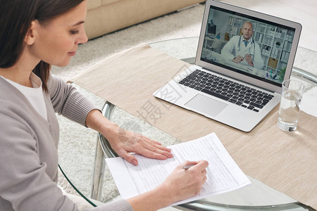 填写健康保险表格并观看医生提供医疗建议的在线视图片
