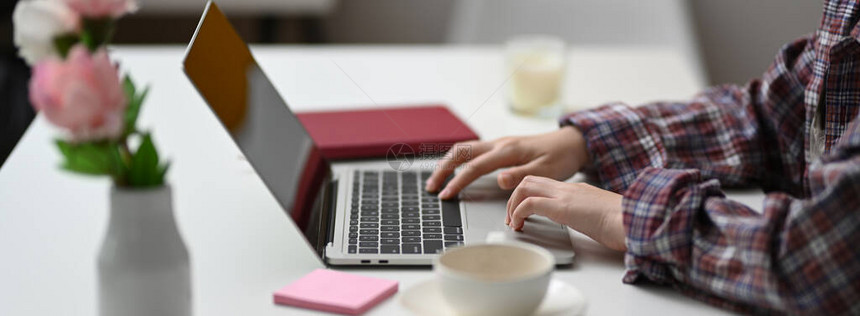 坐在配备用品和装饰的最低限度工作空间时用膝上型电脑打字的女自由图片