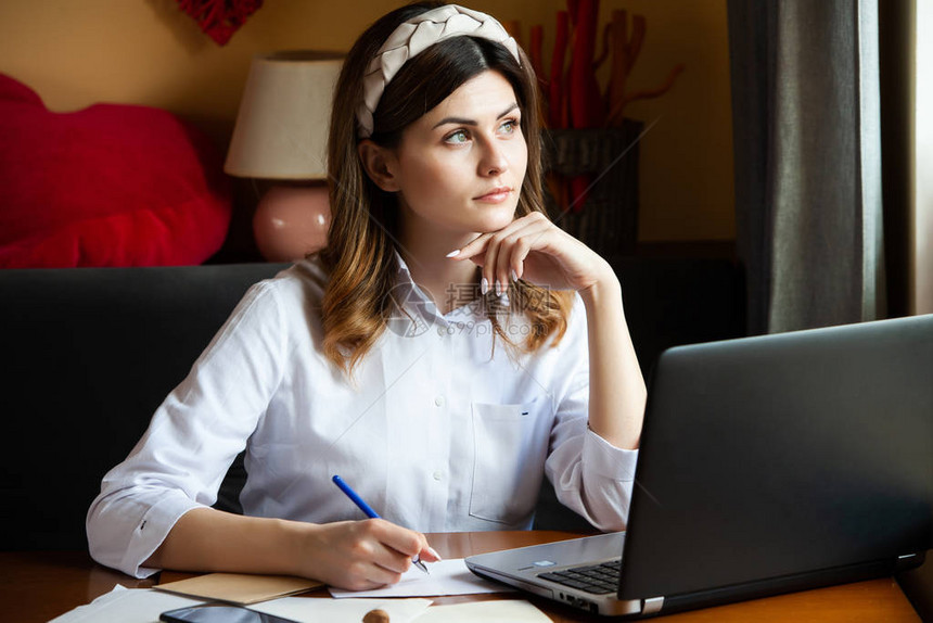 这个女孩在一家咖啡馆的电脑前工作学生在线学习博主年轻的高加索女作家在笔记本电脑上打字有吸引力的女商人在休息期间使用图片