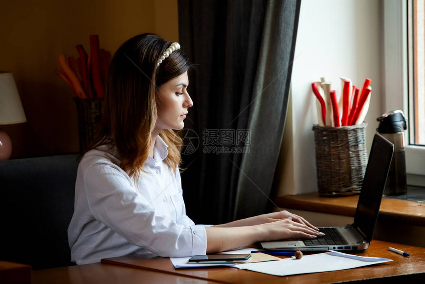 这个女孩在一家咖啡馆的电脑前工作学生在线博主年轻的高加索女作家在笔记本电脑上打字有吸引力的女商人在休息期间使用图片