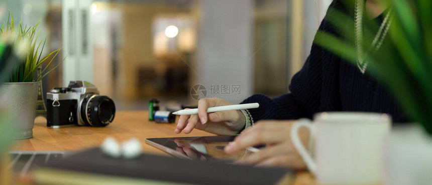 女摄影师在数字平板电脑上工作时用钢笔打在配有照相机和装饰图片