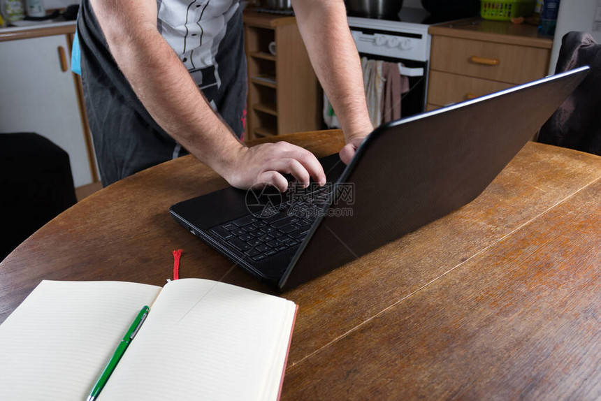 在旧厨房的笔记本电脑上打字的男人旧的图片