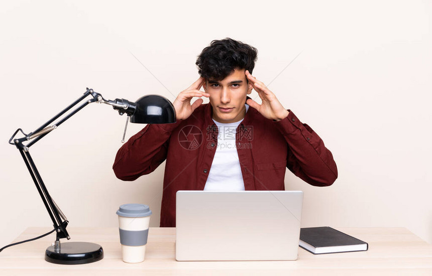 年轻阿根廷男子在工作场所拿着笔记本电脑的桌子上图片
