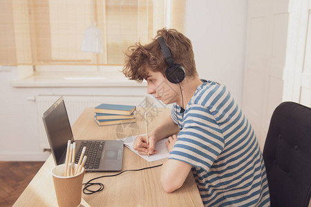 一个戴着耳机的好少年使用笔记本电脑图片