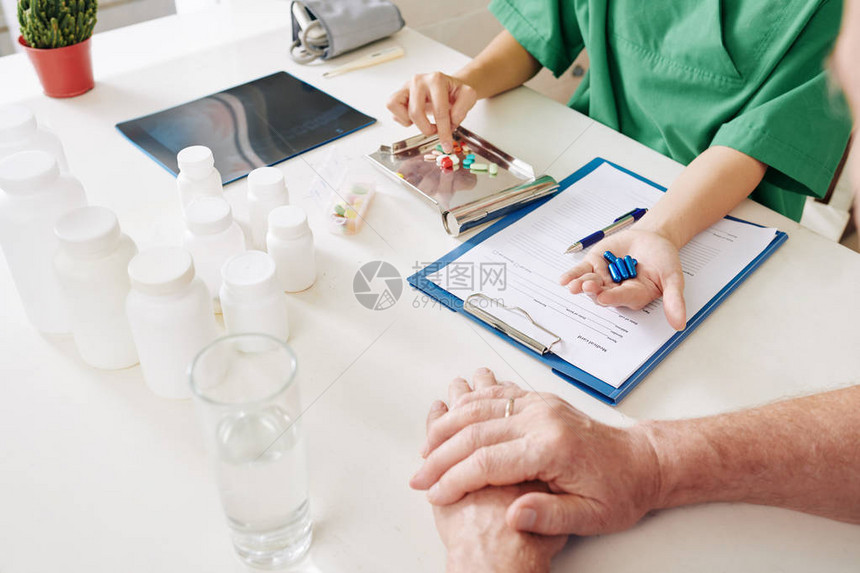 护士填满医疗卡并解释高级病人如何服用药片和药图片