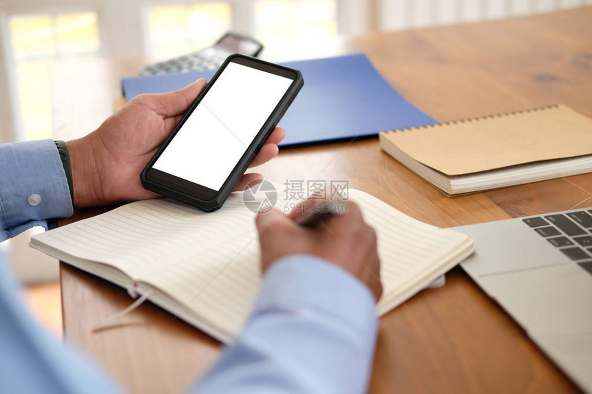 男人在笔记本上写提醒日程表商人在工作场所办公室用智能图片