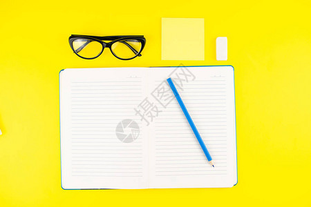 黑色眼镜橡皮擦铅笔记事本计划器和黄色背景上的记事本棒平躺复制空间办公图片