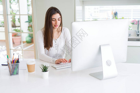 利用计算机工作微笑和专注在线工作的美丽的年轻女商业女青年图片