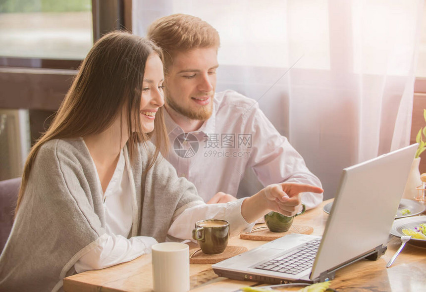 一个男人和一个女人正在家里的一张桌子旁工作已婚夫妇在客厅里用笔记本电脑一个男孩和一个女孩在隔离期间在家工作图片