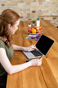使用笔记本电脑和信用卡在桌边杂志和水果附近对自由职业图片