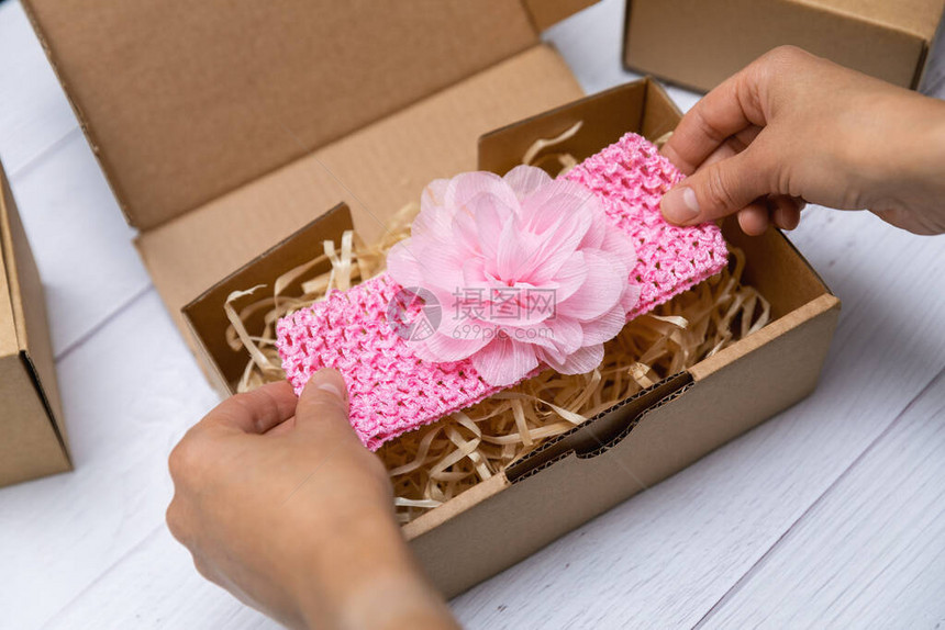 妇女用纸板箱将手工制作的婴儿头巾包装在船图片