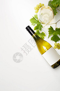 白葡萄酒在玻璃一瓶葡萄和葡萄叶在桌子上一瓶带标签的白葡萄酒瓶样图片